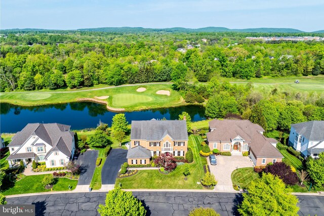 drone / aerial view featuring golf course view, a water view, and a forest view