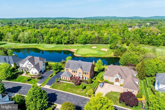 drone / aerial view featuring a water view, a view of trees, golf course view, and a residential view