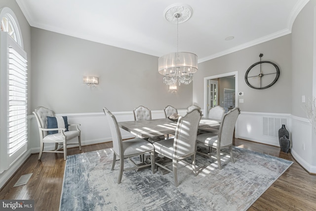 dining space featuring crown molding, an inviting chandelier, wood finished floors, and visible vents