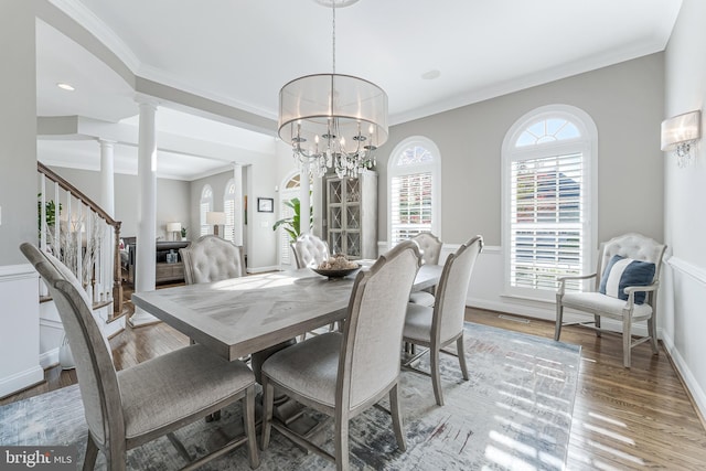 dining room featuring ornamental molding, stairs, decorative columns, a chandelier, and light wood-style flooring