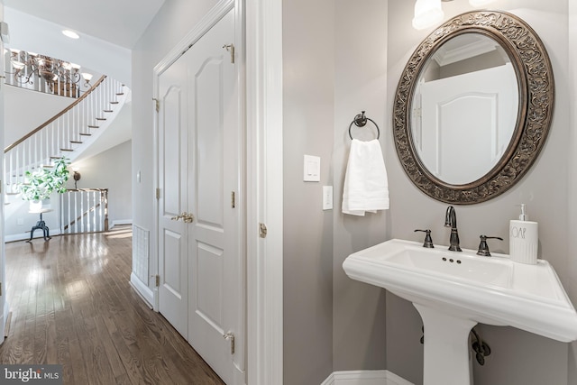 bathroom with baseboards, recessed lighting, a sink, and wood finished floors