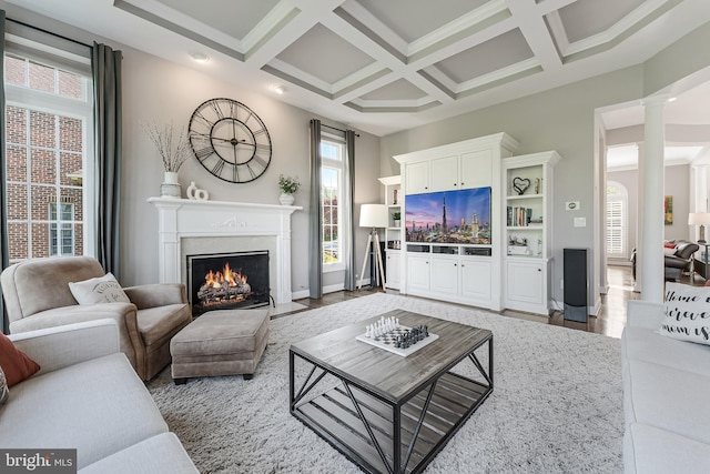 living room featuring decorative columns, beam ceiling, baseboards, a high end fireplace, and coffered ceiling