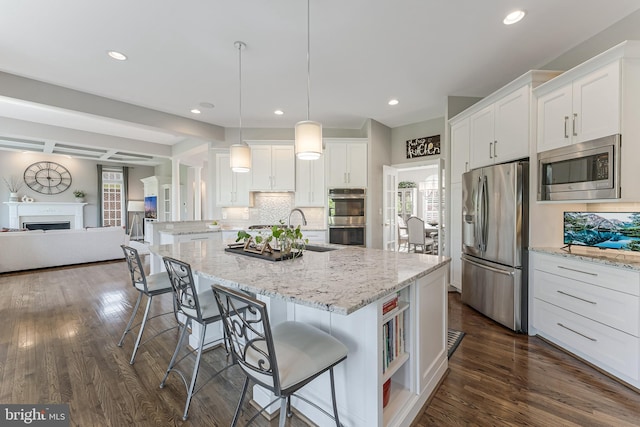 kitchen featuring a kitchen breakfast bar, dark wood-style flooring, appliances with stainless steel finishes, a sink, and white cabinetry