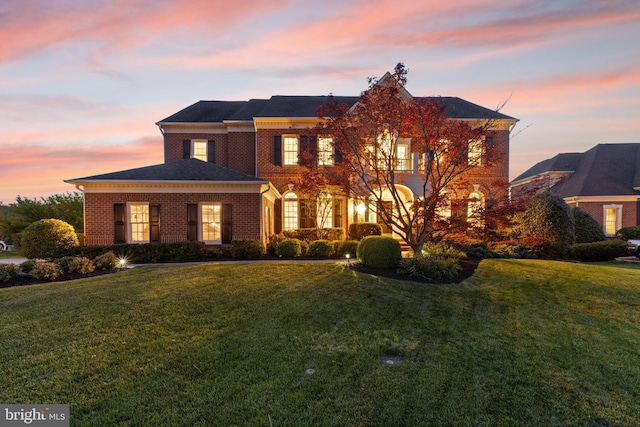 colonial inspired home featuring brick siding and a front lawn