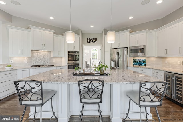 kitchen featuring decorative backsplash, beverage cooler, stainless steel appliances, white cabinetry, and an island with sink
