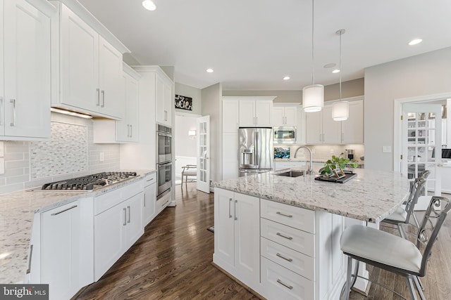 kitchen featuring dark wood-style flooring, stainless steel appliances, a breakfast bar, and a sink
