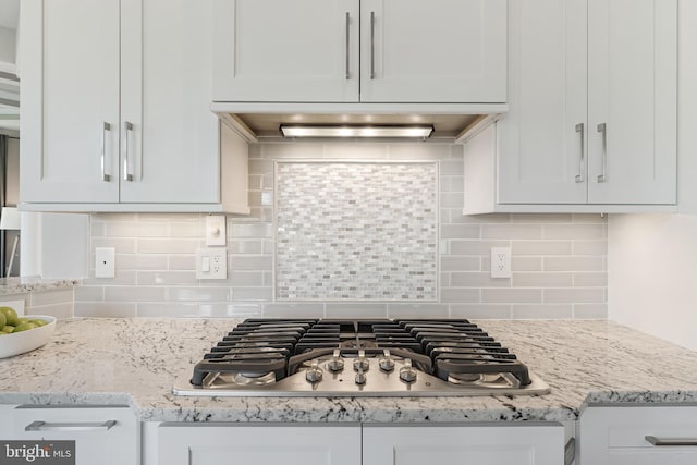 kitchen with white cabinetry, tasteful backsplash, light stone countertops, and stainless steel gas stovetop