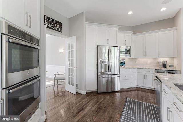 kitchen with dark wood-style flooring, stainless steel appliances, white cabinetry, and decorative backsplash