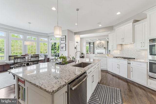 kitchen featuring a sink, a kitchen island with sink, stainless steel appliances, and dark wood finished floors