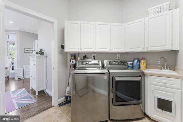 laundry area featuring baseboards, light wood-type flooring, washer and clothes dryer, a sink, and cabinet space