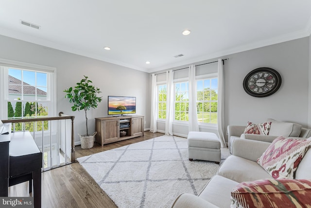 living area with visible vents, recessed lighting, crown molding, and wood finished floors