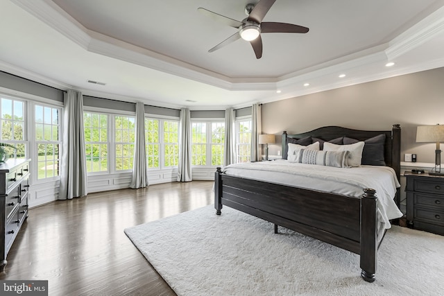 bedroom featuring visible vents, wood finished floors, a raised ceiling, ornamental molding, and recessed lighting