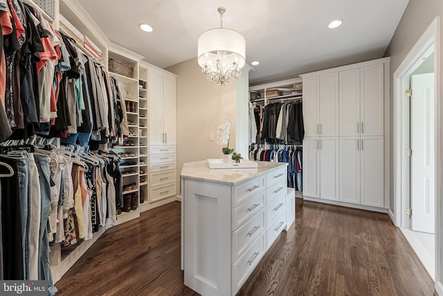 walk in closet with dark wood-type flooring and a notable chandelier