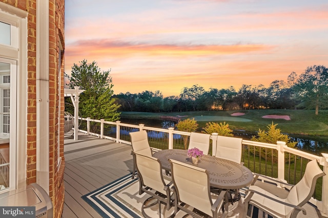 deck with a water view and outdoor dining space