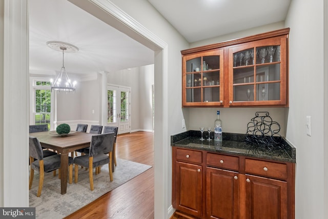 8810 Primula Dr, Laytonsville, MD 20882 - kitchen with light wood finished floors, glass insert cabinets, a chandelier, dark stone countertops, and hanging light fixtures