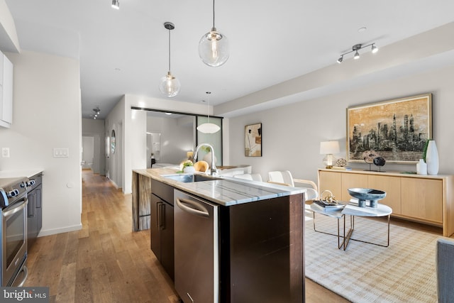 1224 11th St NW Unit 3, Washington, DC 20001 - kitchen with appliances with stainless steel finishes, hanging light fixtures, a sink, light wood-style flooring, and an island with sink
