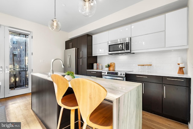 1224 11th St NW Unit 3, Washington, DC 20001 - kitchen with appliances with stainless steel finishes, light wood finished floors, white cabinetry, tasteful backsplash, and modern cabinets