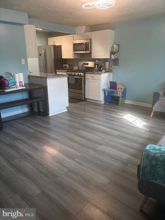 1852 Village Green Dr Unit E-122, Landover, MD 20785 - kitchen featuring appliances with stainless steel finishes, dark wood finished floors, dark stone counters, white cabinetry, and backsplash