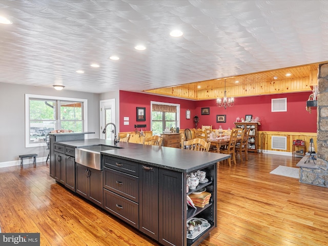 1996 Buck Mountain Rd, Bentonville, VA 22610 - kitchen with a sink, dark countertops, a chandelier, open shelves, and light wood-style floors
