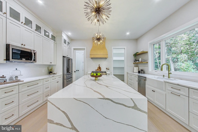 kitchen featuring open shelves, a center island, tasteful backsplash, a sink, and appliances with stainless steel finishes