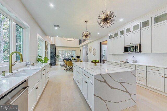 kitchen featuring a sink, appliances with stainless steel finishes, white cabinetry, and decorative light fixtures