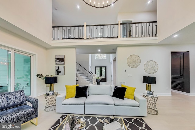 living area featuring stairway, a high ceiling, an inviting chandelier, and visible vents