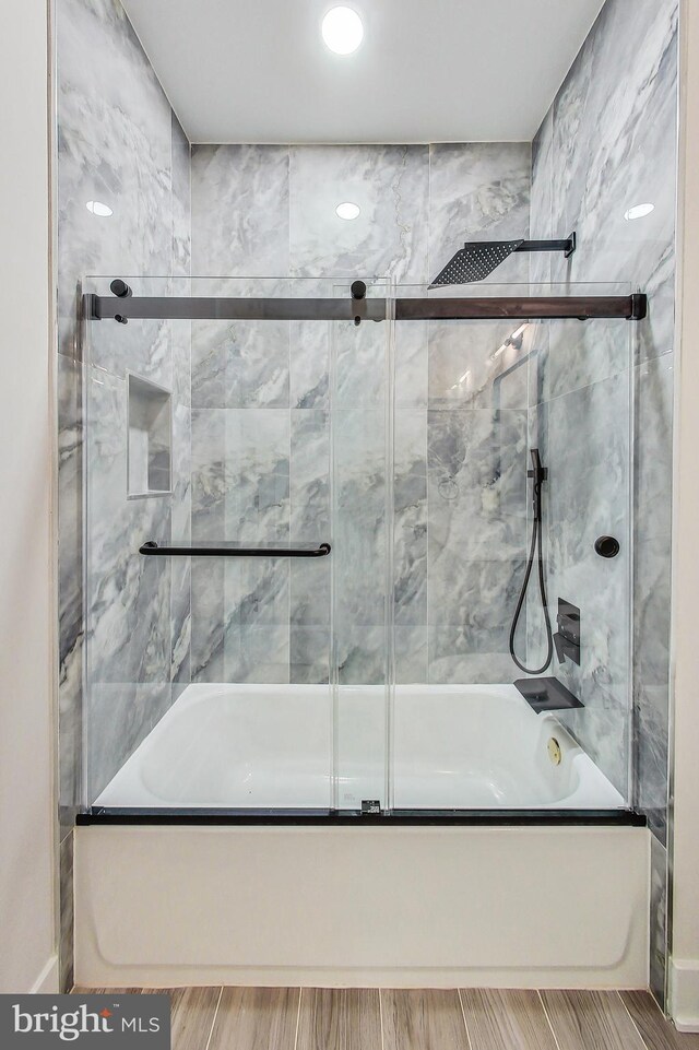 bathroom featuring baseboards, bath / shower combo with glass door, and wood tiled floor