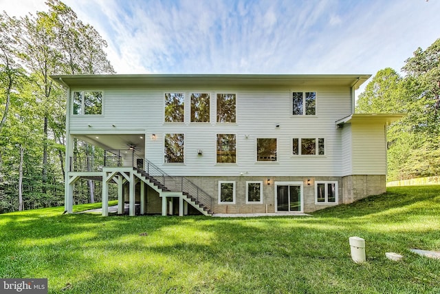 rear view of property with a lawn, ceiling fan, and stairway