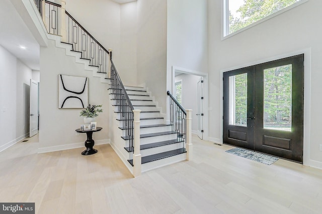 foyer featuring baseboards, wood finished floors, stairway, and a towering ceiling