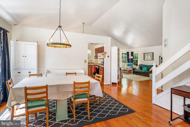 dining area with an inviting chandelier, wood finished floors, and lofted ceiling