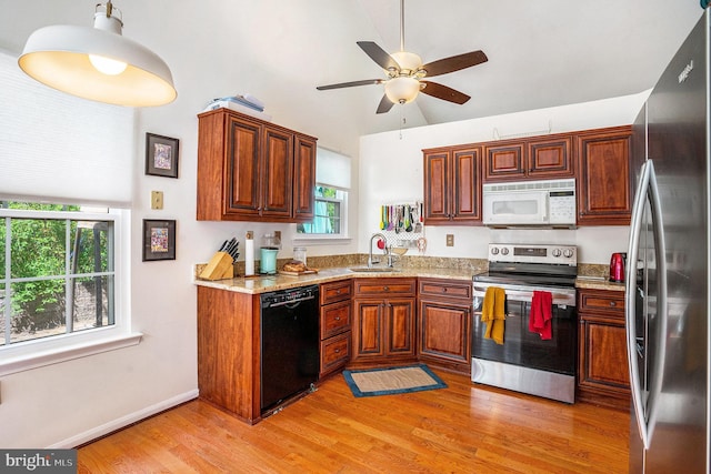 kitchen with a ceiling fan, lofted ceiling, a sink, light wood finished floors, and stainless steel appliances
