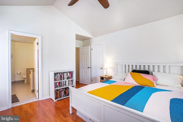 bedroom featuring a ceiling fan, vaulted ceiling, light wood-style flooring, and ensuite bathroom