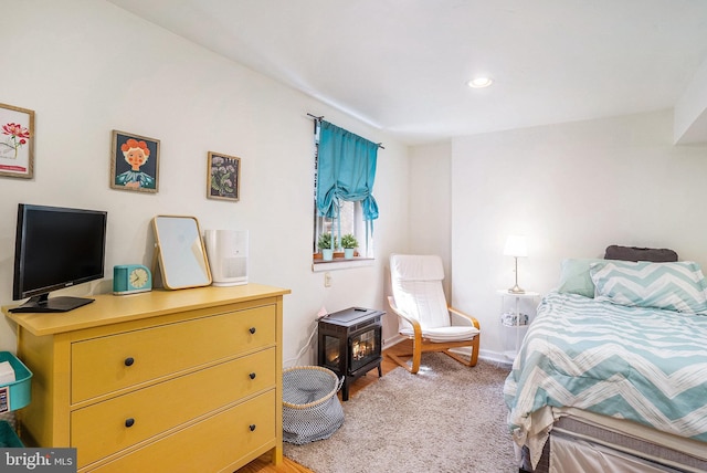 bedroom with recessed lighting, baseboards, a wood stove, and light wood-type flooring