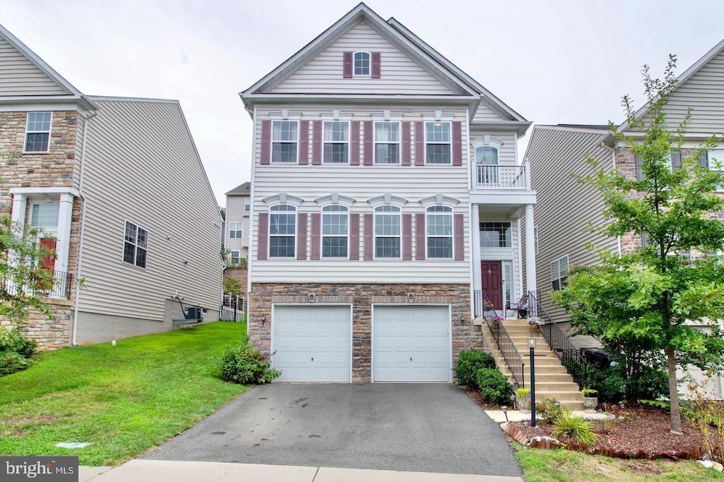 view of front of house with an attached garage, a front lawn, aphalt driveway, and stone siding