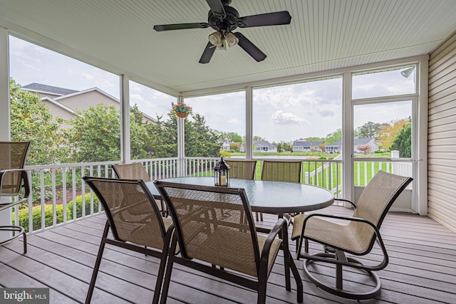 sunroom with outdoor dining space, ceiling fan, and a residential view