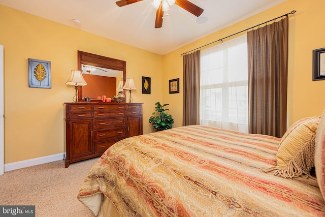 bedroom featuring a ceiling fan, light carpet, and baseboards