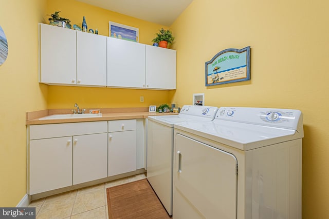 laundry area with light tile patterned floors, separate washer and dryer, a sink, and cabinet space