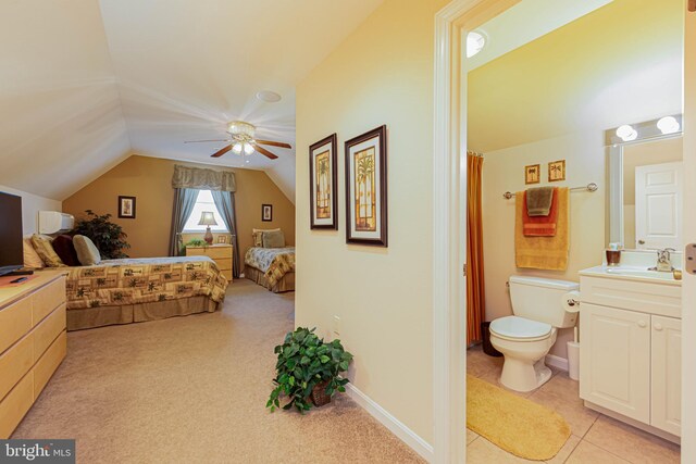 bedroom with ensuite bath, light colored carpet, vaulted ceiling, a sink, and baseboards