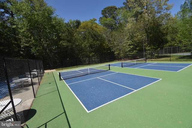 view of tennis court with community basketball court and fence