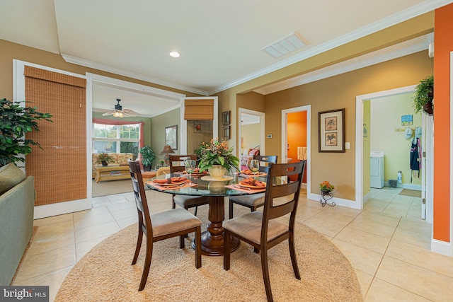 dining room featuring light tile patterned floors, ornamental molding, washer / dryer, and baseboards