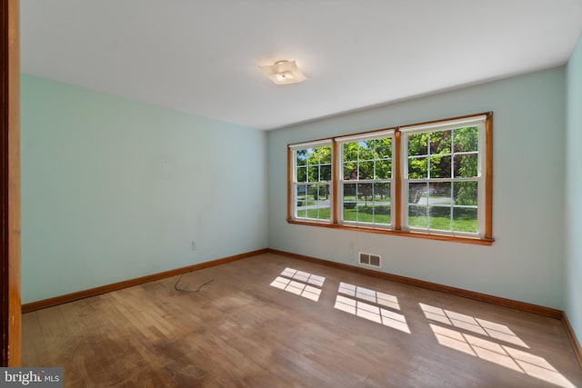 spare room featuring baseboards and wood finished floors