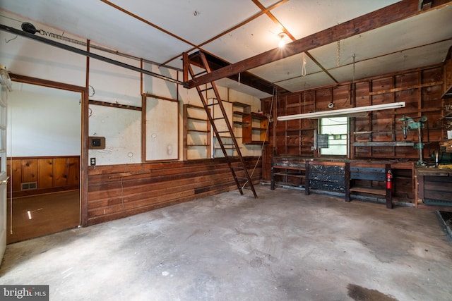 garage featuring wooden walls, a workshop area, and wainscoting