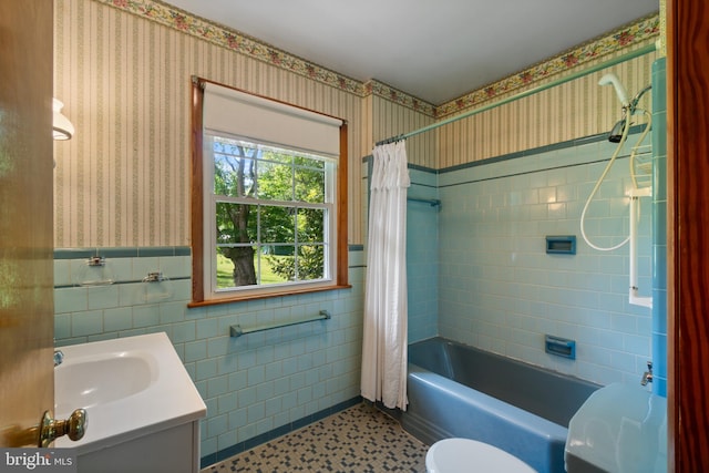 full bath with wallpapered walls, toilet, shower / bath combination with curtain, wainscoting, and vanity