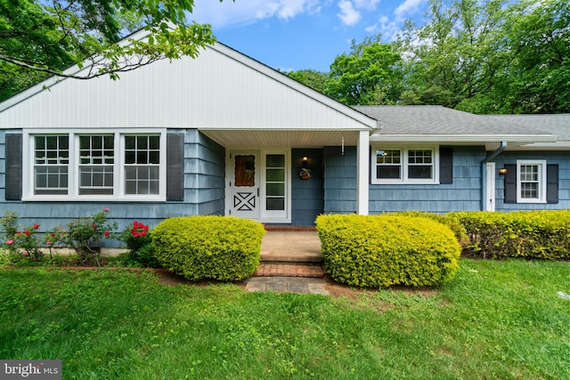 view of front of property with a front yard, a porch, and roof with shingles