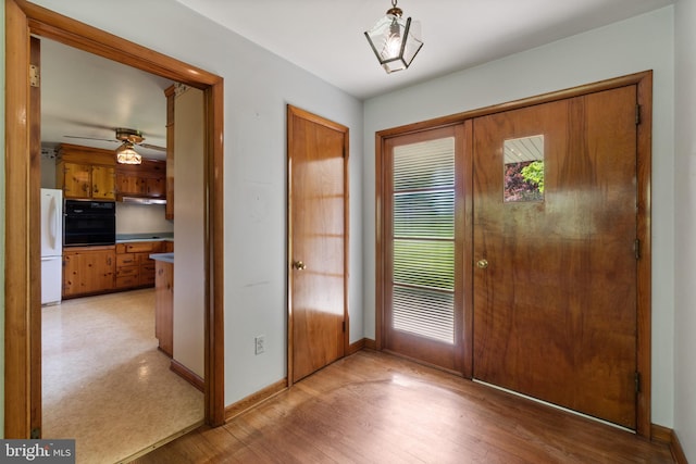 entryway featuring baseboards, a ceiling fan, and light wood-style floors