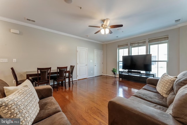 living area featuring crown molding, a ceiling fan, visible vents, and wood finished floors