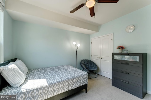 bedroom with a ceiling fan, a closet, and light colored carpet