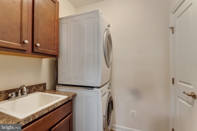 washroom with a sink, cabinet space, and stacked washer / drying machine