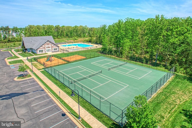 view of sport court with a community pool and fence