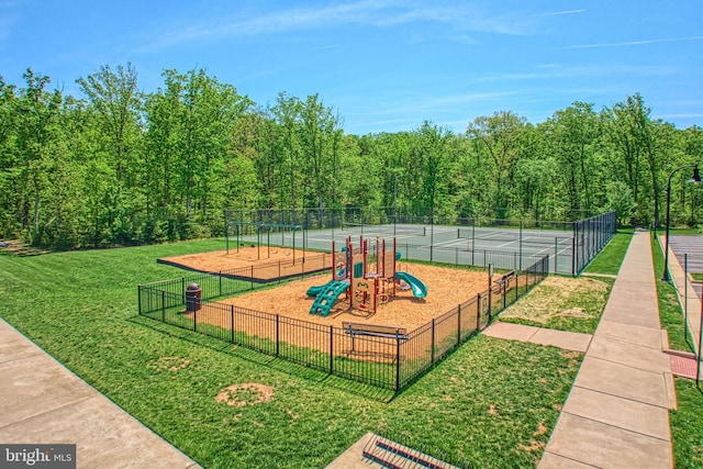 view of community featuring a lawn, fence, and playground community